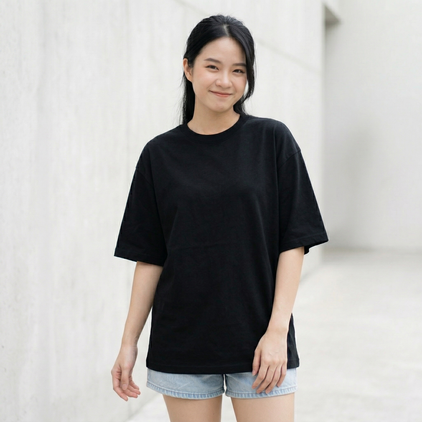 Woman wearing black oversized t-shirt front view relaxed fit minimal streetwear style