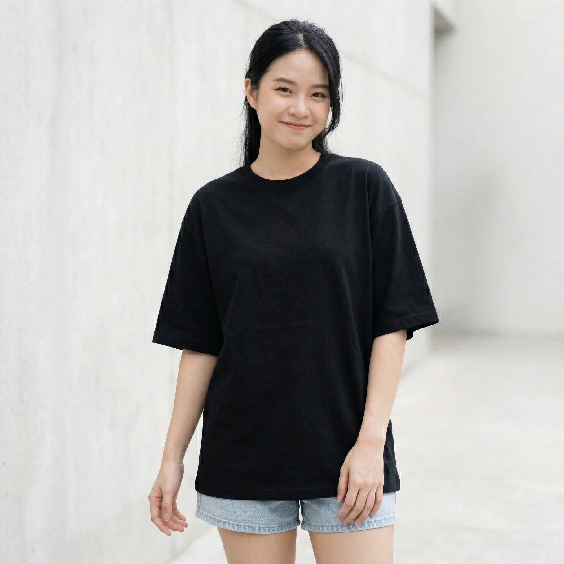 Woman wearing black oversized t-shirt front view relaxed fit minimal streetwear style
