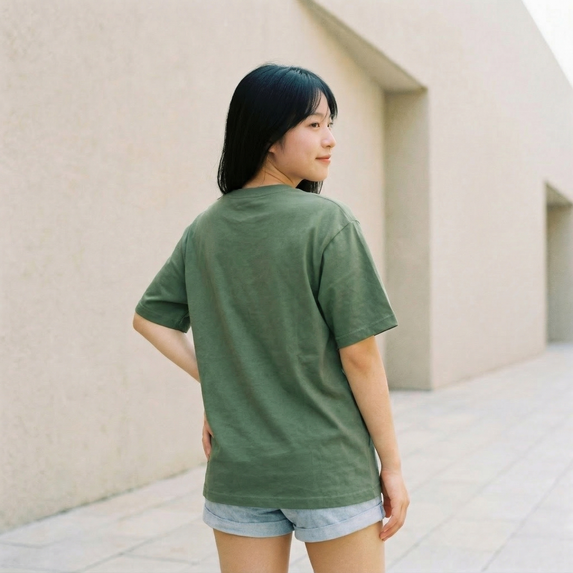 Woman wearing green oversized t-shirt back view relaxed fit casual minimal streetwear