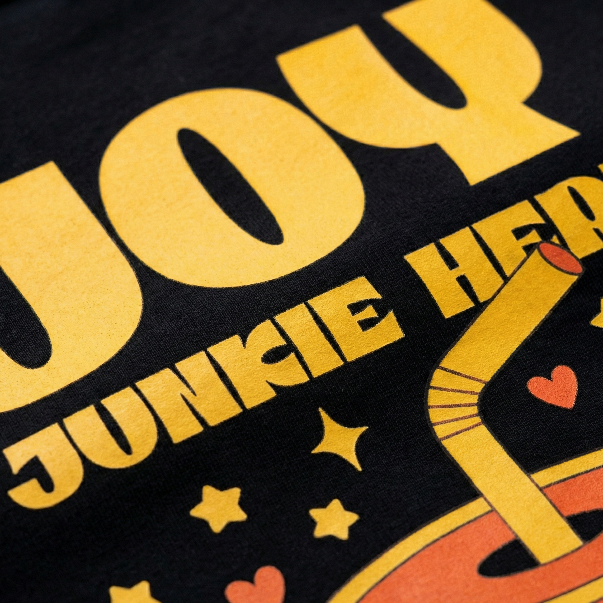 Close-up of “Joy Junkie Here” yellow print and cute drink illustration on black t-shirt