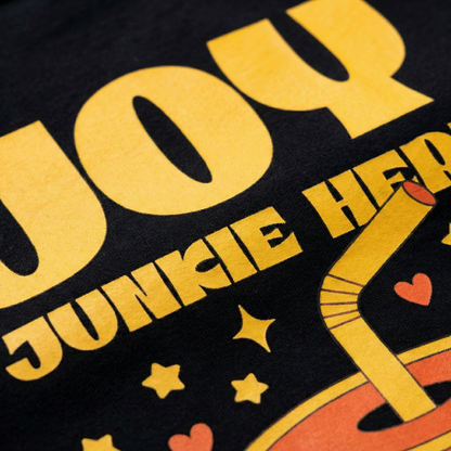 Close-up of “Joy Junkie Here” yellow print and cute drink illustration on black t-shirt